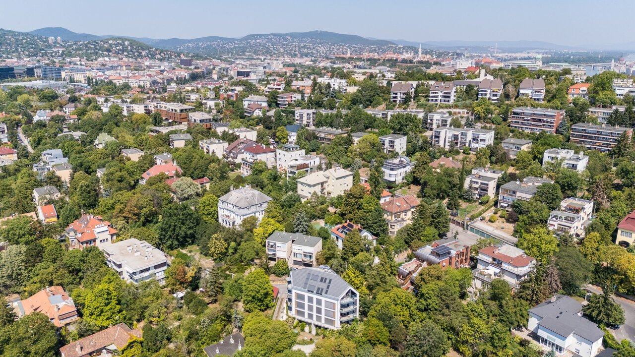 Légi panoráma a zöldövezeti gellérthegyi lakónegyedről, a budai hegyekkel és a pesti városképpel a háttérben